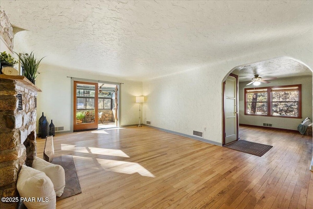 living room with ceiling fan, a textured ceiling, light hardwood / wood-style floors, and a healthy amount of sunlight