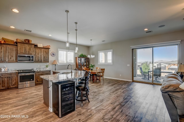 kitchen with a kitchen bar, stainless steel appliances, sink, a large island with sink, and wine cooler