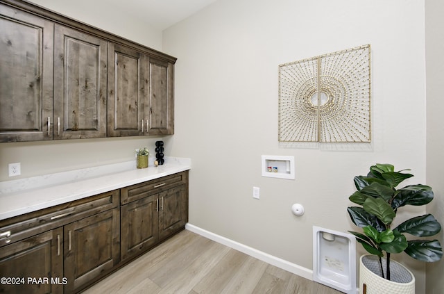 clothes washing area featuring gas dryer hookup, baseboards, hookup for a washing machine, light wood finished floors, and cabinet space