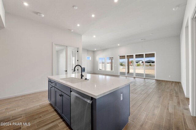 kitchen featuring sink, dishwasher, a kitchen island with sink, and light hardwood / wood-style flooring