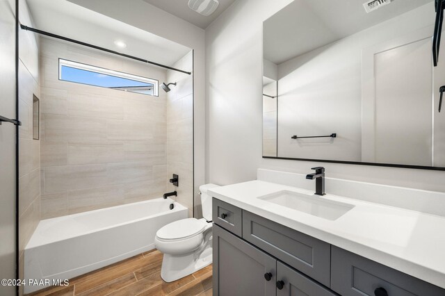 full bathroom with tiled shower / bath, vanity, and toilet