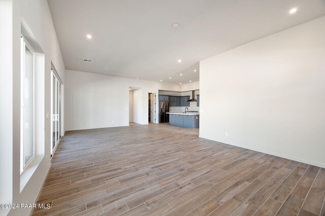 unfurnished living room with sink and light hardwood / wood-style floors