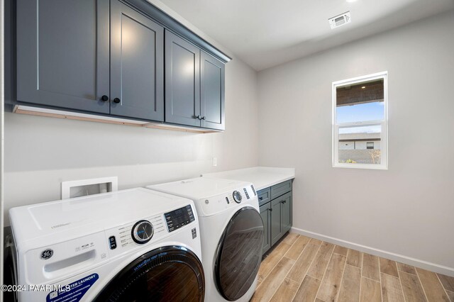 laundry area with independent washer and dryer, cabinets, and light hardwood / wood-style flooring