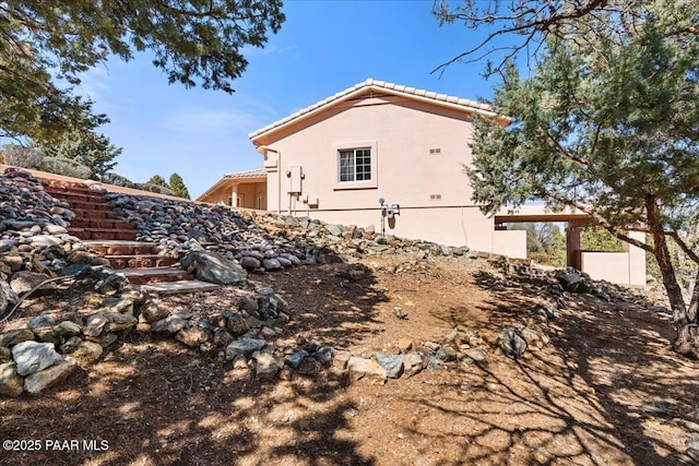 view of home's exterior with stucco siding and a tile roof