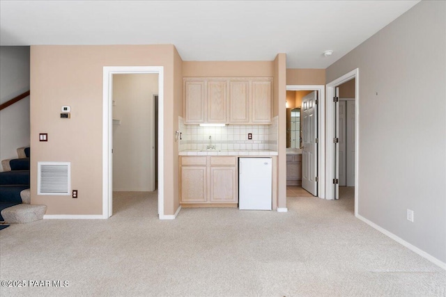 kitchen with visible vents, refrigerator, light brown cabinetry, tile counters, and light colored carpet