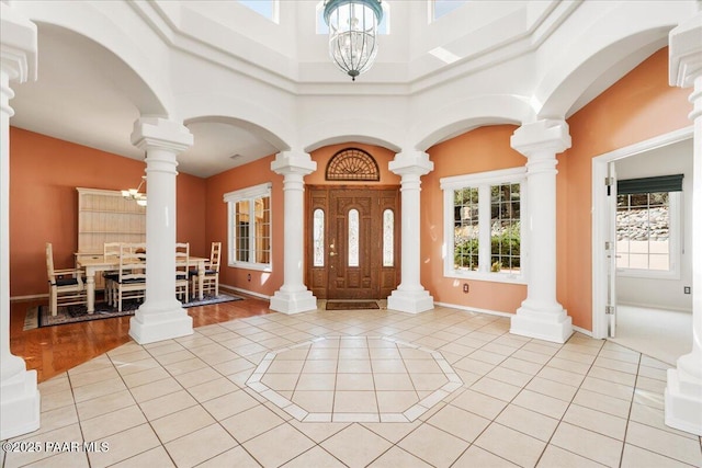 entryway with an inviting chandelier, light tile patterned floors, baseboards, and a towering ceiling