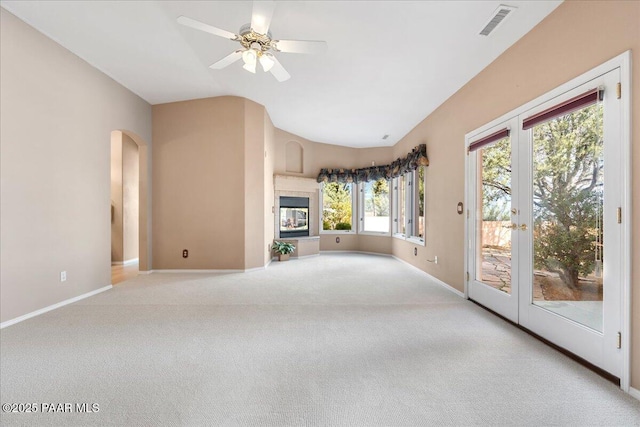 unfurnished living room featuring a ceiling fan, visible vents, french doors, a tiled fireplace, and carpet flooring