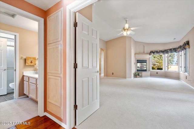 corridor featuring baseboards, carpet floors, arched walkways, and vaulted ceiling