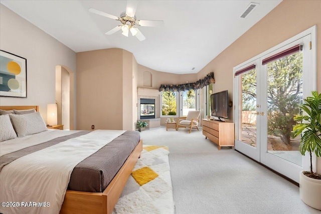 carpeted bedroom with visible vents, lofted ceiling, arched walkways, french doors, and access to outside