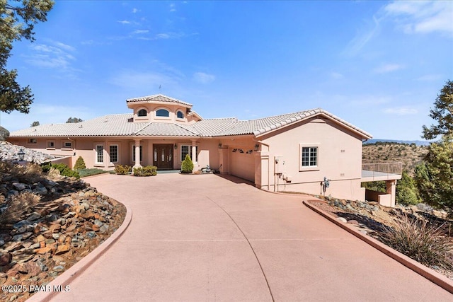 mediterranean / spanish house with stucco siding, a tiled roof, concrete driveway, and a garage