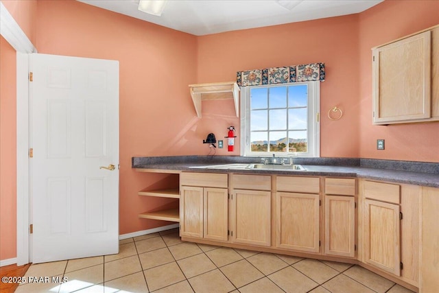 kitchen with light brown cabinetry, light tile patterned floors, dark countertops, and open shelves