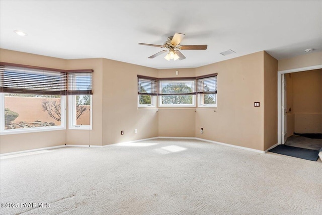 spare room with visible vents, carpet floors, baseboards, and a ceiling fan