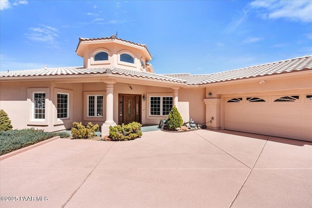 mediterranean / spanish house featuring a tile roof, an attached garage, driveway, and stucco siding