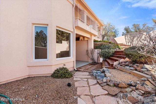 view of side of home with stucco siding and a balcony