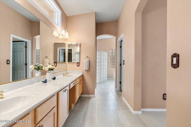 bathroom with double vanity, tile patterned floors, baseboards, and a sink