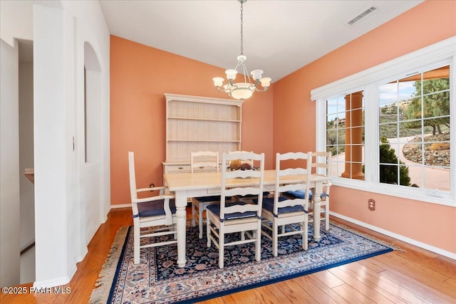 dining room with visible vents, baseboards, a chandelier, vaulted ceiling, and hardwood / wood-style flooring