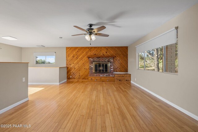 2615 W Red Tail Way, Prescott, AZ 86305 - unfurnished living room featuring ceiling fan, baseboards, light wood finished floors, wooden walls, and a brick fireplace