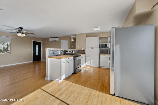 2615 W Red Tail Way, Prescott, AZ 86305 - kitchen featuring stainless steel appliances, wooden counters, a wall mounted AC, white cabinetry, and light wood finished floors