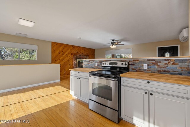 2615 W Red Tail Way, Prescott, AZ 86305 - kitchen featuring stainless steel electric range oven, butcher block counters, a wall mounted air conditioner, a ceiling fan, and wood walls