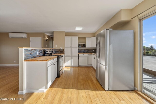 2615 W Red Tail Way, Prescott, AZ 86305 - kitchen featuring appliances with stainless steel finishes, a wall unit AC, light wood-style flooring, and tasteful backsplash