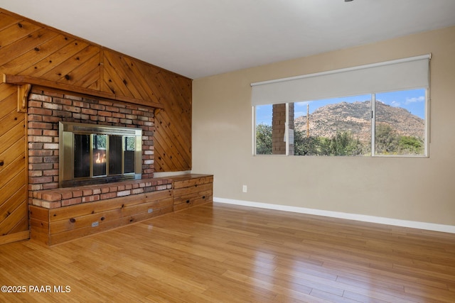 2615 W Red Tail Way, Prescott, AZ 86305 - unfurnished living room with baseboards, wood finished floors, wooden walls, a fireplace, and a mountain view