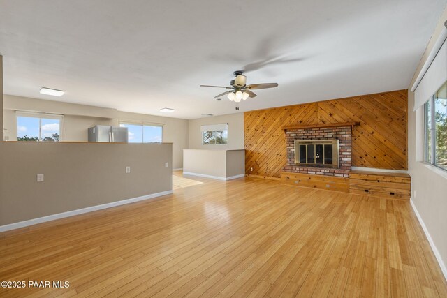 2615 W Red Tail Way, Prescott, AZ 86305 - unfurnished living room with a ceiling fan, baseboards, wood walls, healthy amount of natural light, and light wood-type flooring