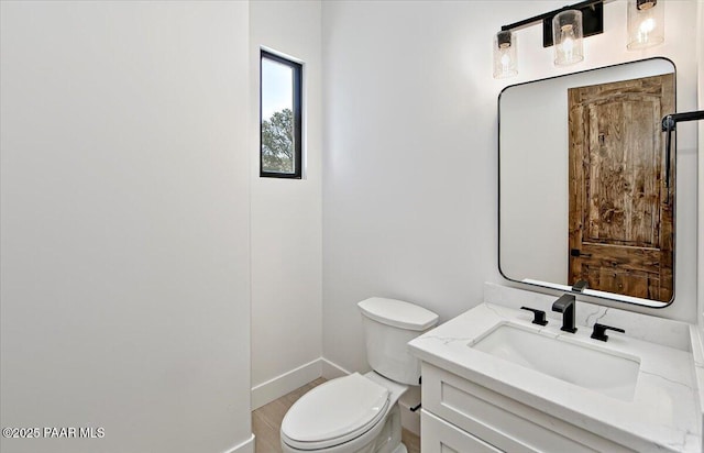 bathroom featuring toilet, vanity, and baseboards