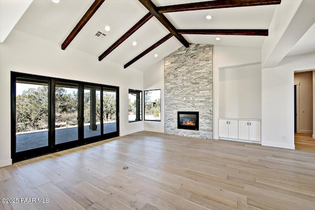 unfurnished living room with light wood finished floors, a fireplace, baseboards, beam ceiling, and visible vents