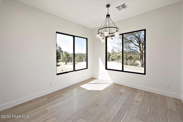 unfurnished room with baseboards, a notable chandelier, visible vents, and light wood-style flooring