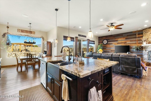kitchen with wooden walls, a sink, ceiling fan, beverage cooler, and stainless steel dishwasher