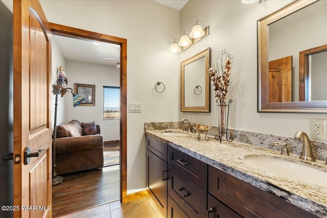 bathroom featuring a sink, baseboards, double vanity, and tile patterned flooring