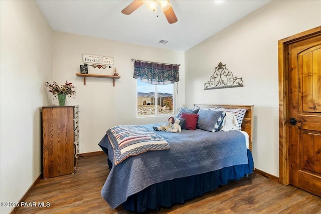bedroom featuring visible vents, ceiling fan, baseboards, and wood finished floors