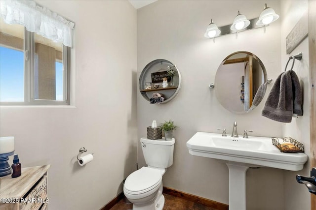 half bathroom featuring baseboards and toilet