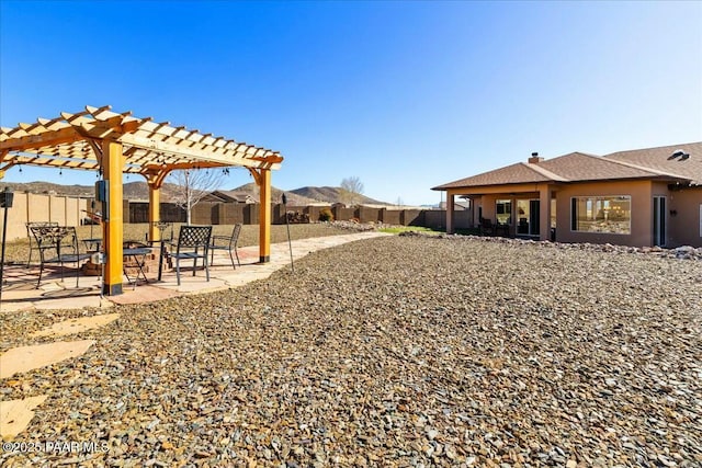 view of yard featuring a mountain view, a patio, a fenced backyard, and a pergola