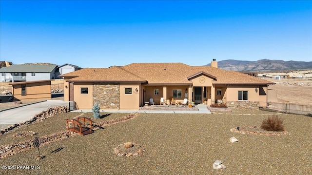view of front of house featuring a mountain view, stucco siding, a chimney, and fence