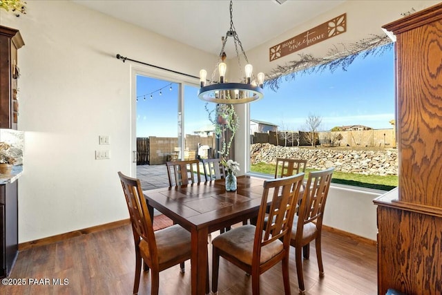 dining space featuring baseboards, an inviting chandelier, and wood finished floors