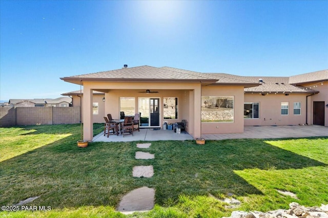 rear view of house with ceiling fan, fence, stucco siding, a yard, and a patio area