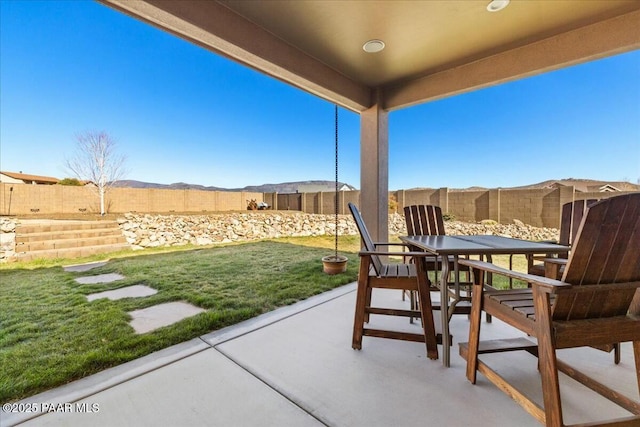 view of patio featuring outdoor dining space, a fenced backyard, and a mountain view