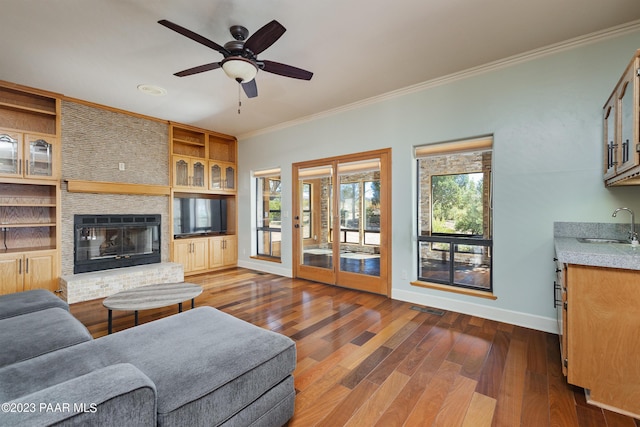 living room featuring dark hardwood / wood-style flooring, a brick fireplace, ceiling fan, and crown molding