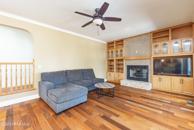 living room featuring a fireplace, crown molding, hardwood / wood-style floors, and ceiling fan