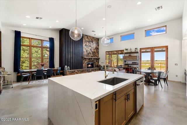 kitchen featuring dishwasher, visible vents, a sink, finished concrete floors, and a fireplace
