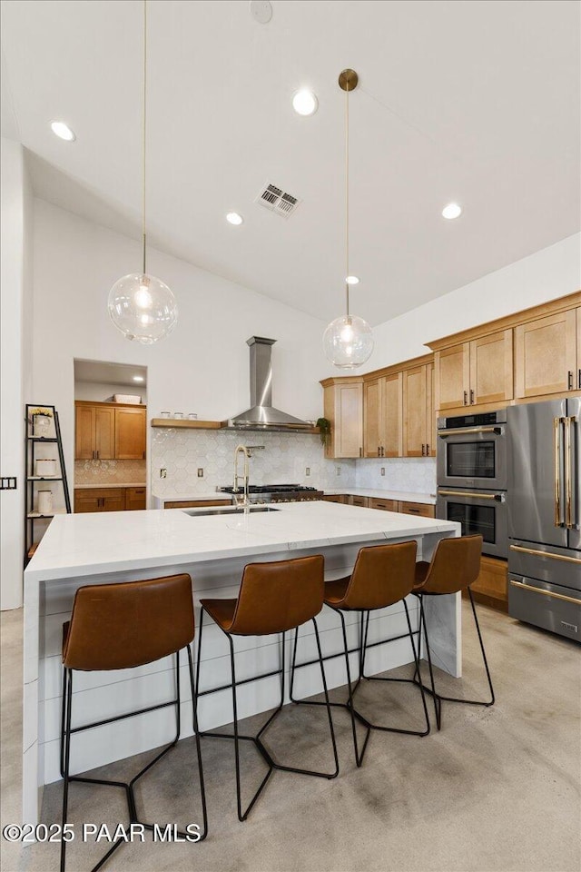 kitchen featuring a sink, stainless steel appliances, backsplash, wall chimney exhaust hood, and visible vents