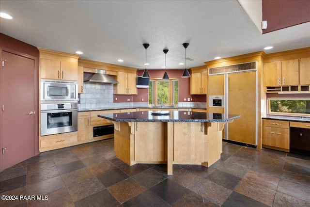 414 N Fitzmaurice Dr, Prescott, AZ 86303 - kitchen featuring wall chimney exhaust hood, dark stone counters, a kitchen island, a breakfast bar area, and built in appliances