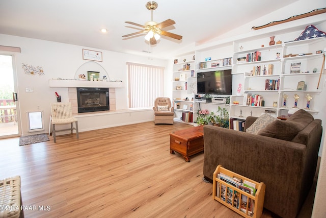 living room with ceiling fan, a fireplace, light hardwood / wood-style floors, and lofted ceiling