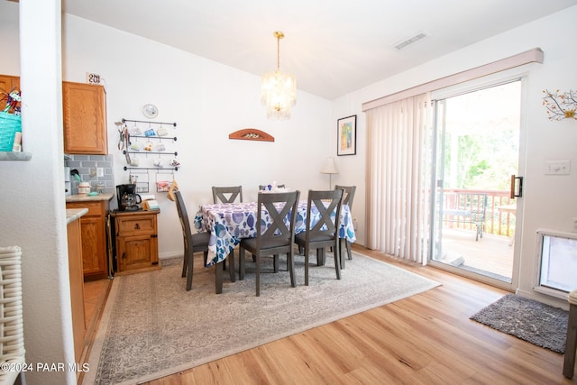 dining space with radiator heating unit, light wood-type flooring, an inviting chandelier, and a healthy amount of sunlight