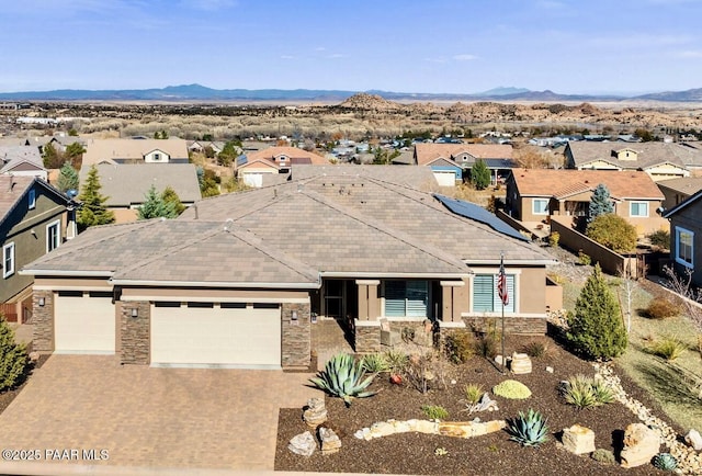 ranch-style home featuring a garage, stone siding, a residential view, and driveway