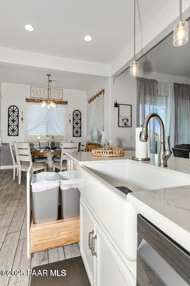 kitchen with hanging light fixtures, light stone countertops, and white cabinets