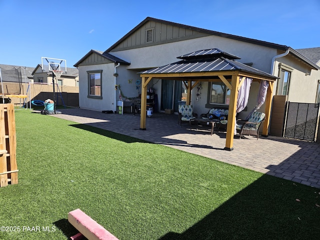 rear view of house featuring a gazebo, a yard, a patio, and a trampoline