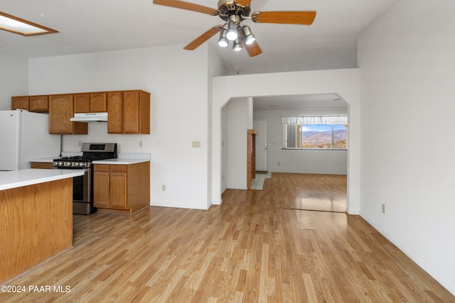 15015 E White Dr, Dewey-Humboldt, AZ 86327 - kitchen with gas stove, freestanding refrigerator, under cabinet range hood, brown cabinetry, and light countertops