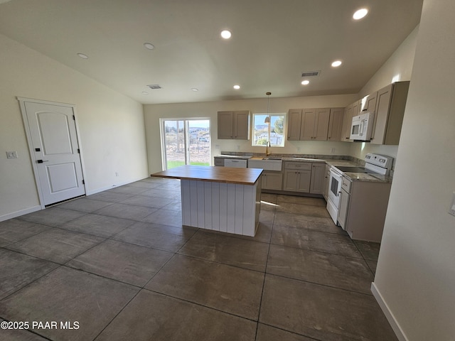 kitchen with white appliances, sink, pendant lighting, a center island, and lofted ceiling